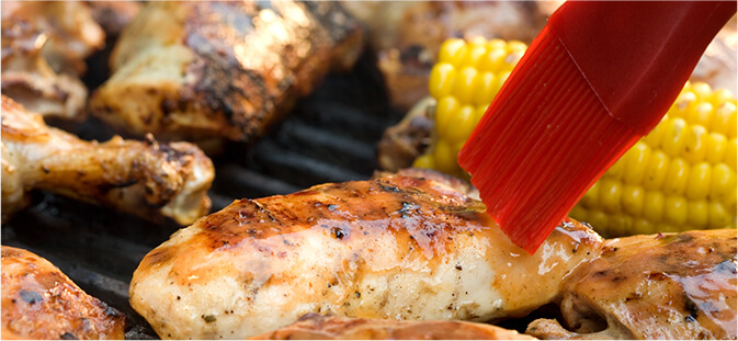 Grilled chicken on barbecue with basting brush